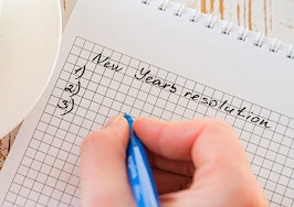 A hand penning New Year's resolutions
