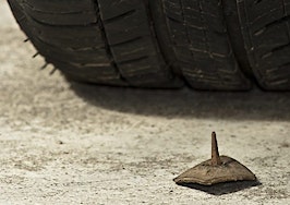 A tire about to drive over a rusty nail