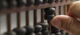A hand moving beads on an abacus