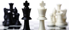 Black and white chess pieces facing each other across a board