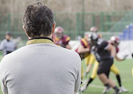 A shot of a coach watching his football team practice