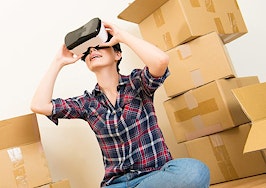 A woman looks through a virtual reality headset in the midst of boxes