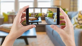 hands holding up smart phone to take a picture of a living room
